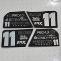 Four black foam decals with white and silver graphics for a racing livery, featuring the number 11 and sponsor logos like Prickly, ChiBattery, Guts, Thrill Seekers, and Fox, arranged on a white pegboard background.