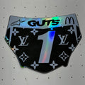 A novelty sticker shaped like a pair of underwear, featuring a black background with the Louis Vuitton monogram pattern, a large holographic number '1' in the center, 'GUTS' in black text at the top, and a McDonald's arches logo on the right side.