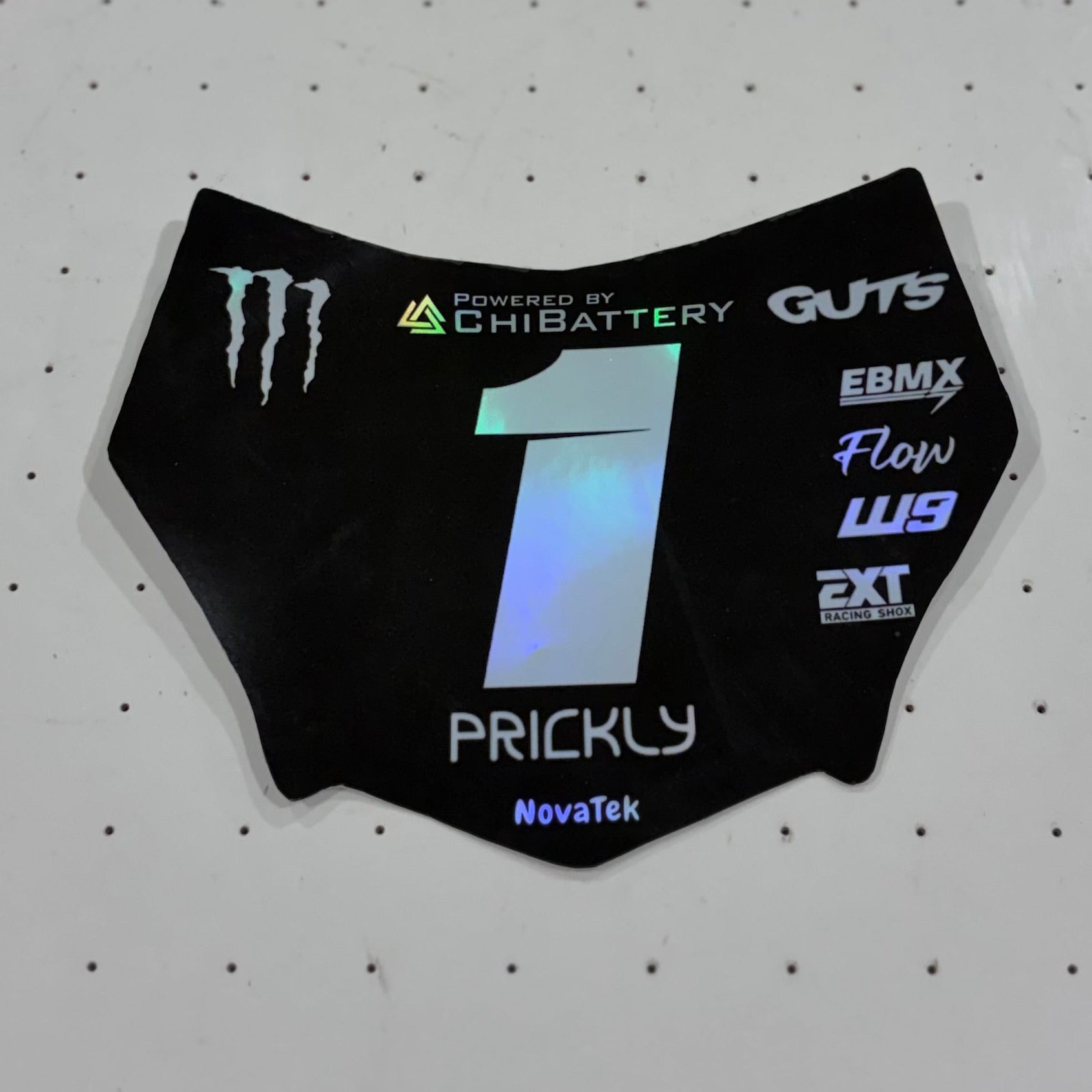 A custom motorcycle number plate skin or decal with the number 1 and sponsor logos, displayed on a white perforated sheet.