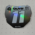 A holographic black and white NovaTek Guts 11 sticker on a white perforated surface.