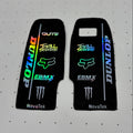 Two black motorcycle tank decal stickers with various sponsor logos, including Dunlop, Fox Racing, EBM X, and Monster Energy, displayed on a white pegboard background.